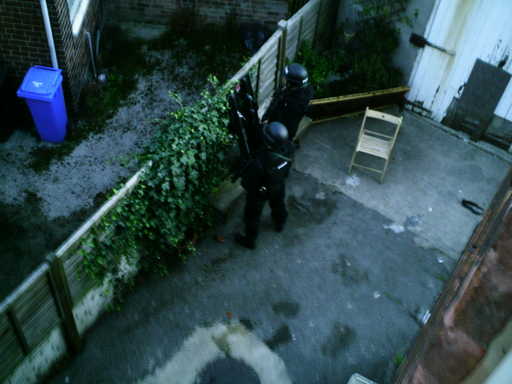 Police wait in a nearby garden